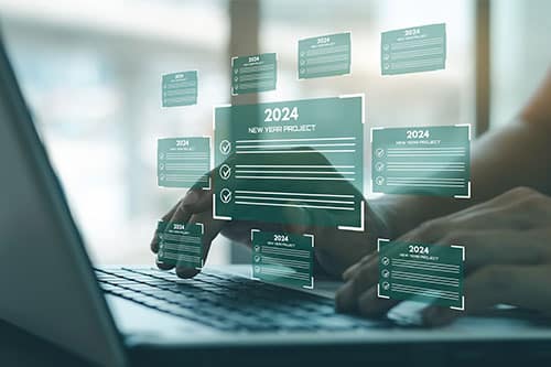 Year-End Legal Trends Impacting Business | Niswanger Law Analysis. Image of female hands typing on laptop keyboard with 2024 new year business plan icons.