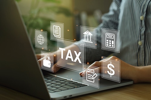 Tax Lawyers in Business Planning | Niswanger Law Financial Insights. Image of woman using laptop with financial research, government taxes and calculations icons.